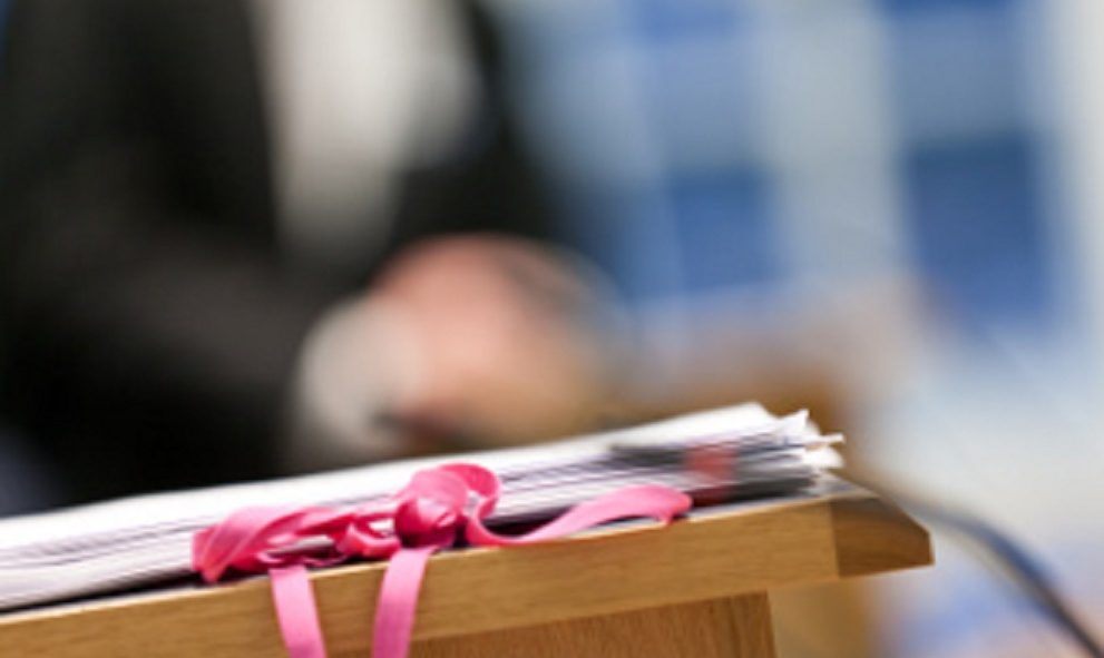 legal documents in foreground with blurred person in barrister attire in background